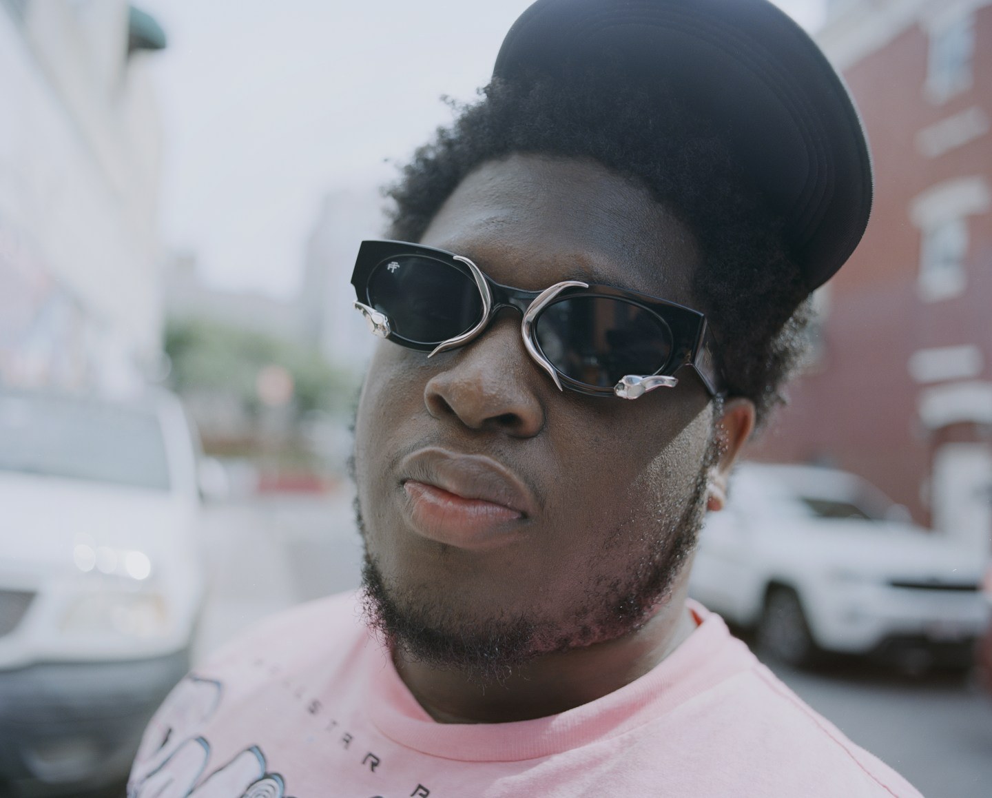 Solo portrait of Cash Cobain in a pink shirt and sunglasses